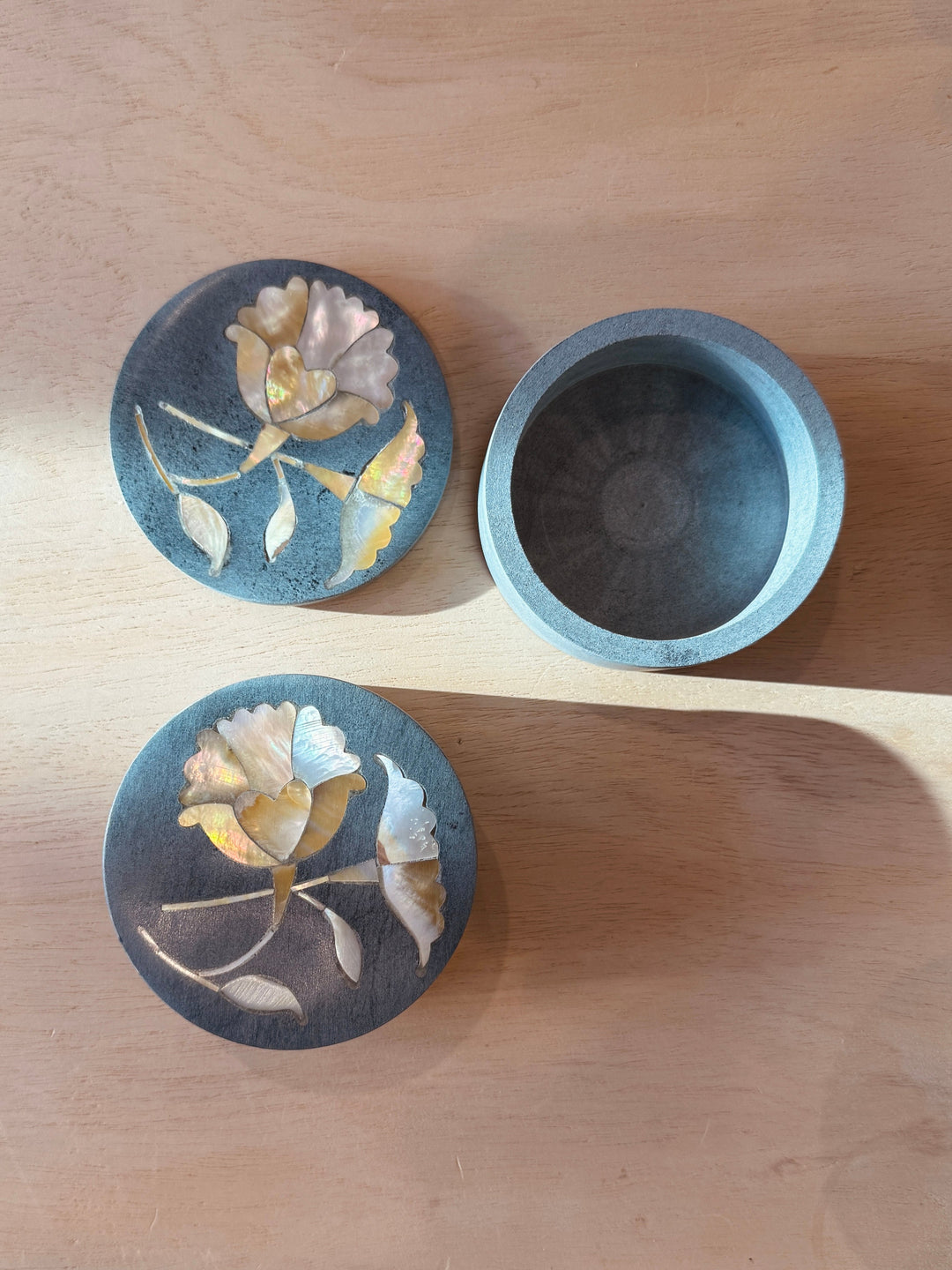 Two stone containers with floral designs on a wooden surface