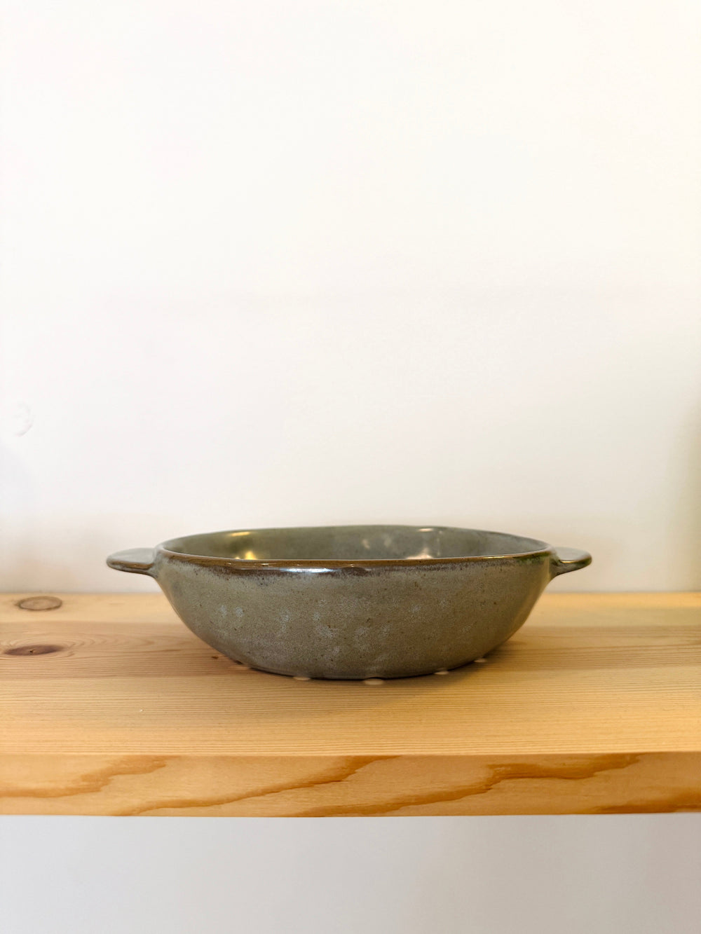 Gray ceramic bowl on a wooden surface with a white background