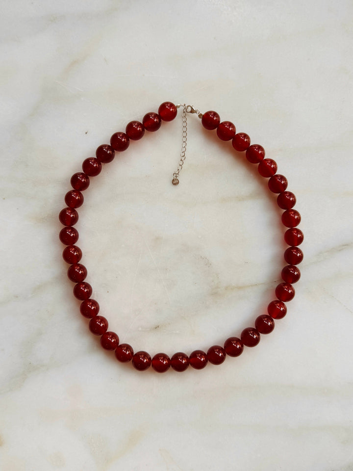 Red beaded necklace on a marble surface