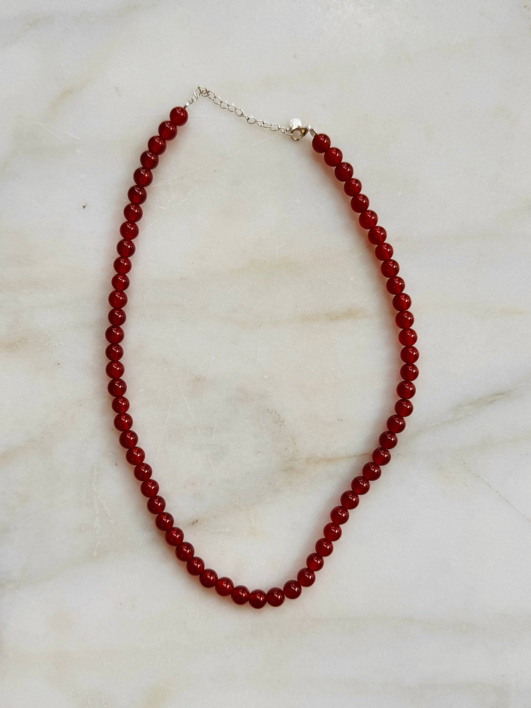 Red beaded necklace on a marble surface