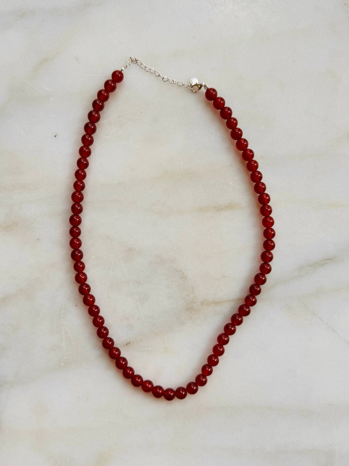 Red beaded necklace on a marble surface