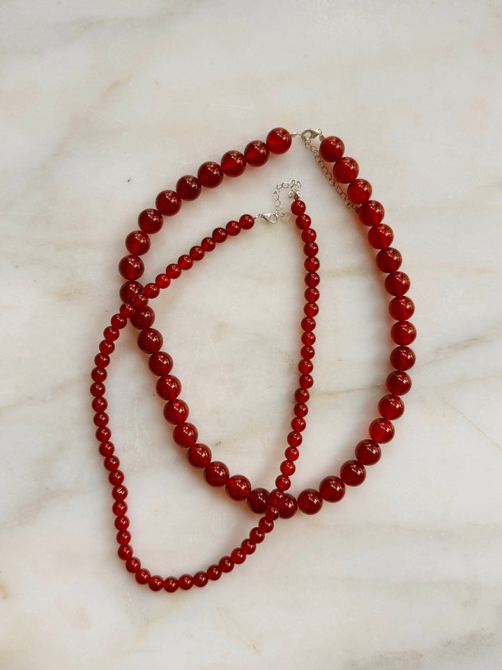 Red beaded necklace on a marble surface