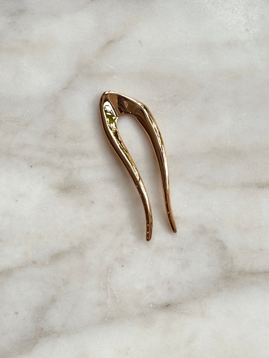 Gold hair pin on a marble surface
