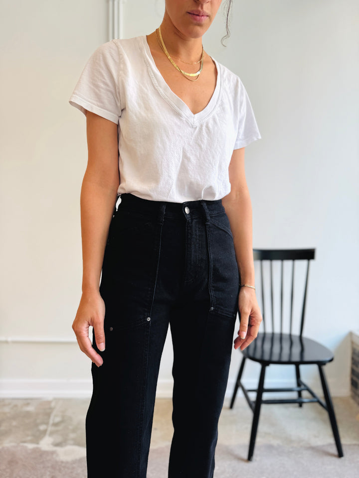 Person wearing a white t-shirt and black pants in a minimal indoor setting